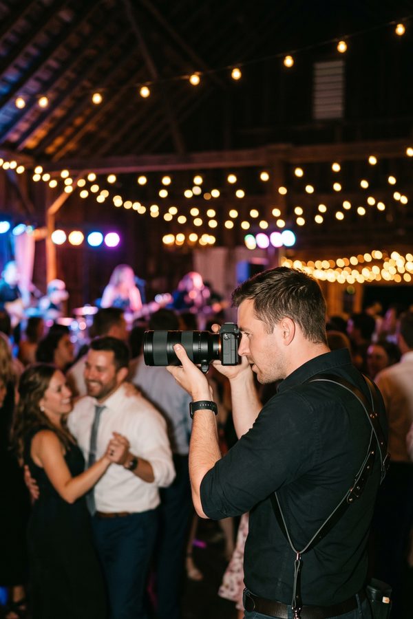 A wedding photographer shooting with a telephoto lens on the dance floor at a night wedding