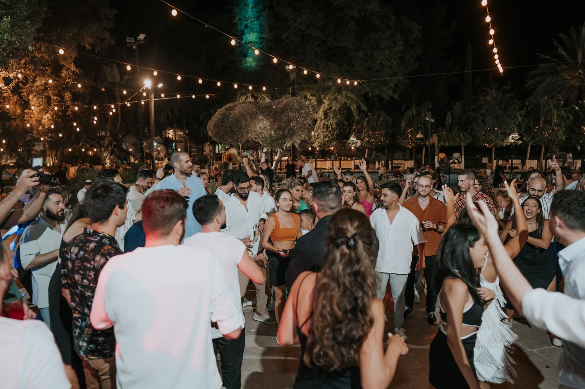 A dance floor full of guests at a night wedding